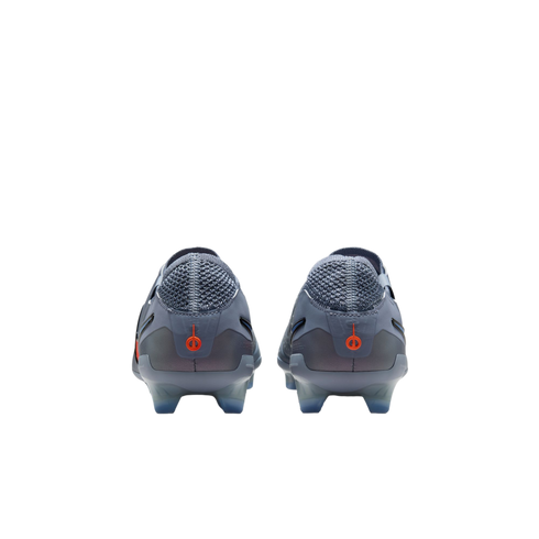 Rear view of a pair of light grey soccer cleats featuring orange circular logos on the heels, against a black background.