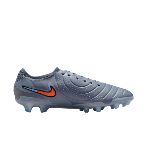Profile view of a grey Nike soccer cleat featuring a textured upper, an orange and blue swoosh, and translucent blue studs, set against a solid black background.