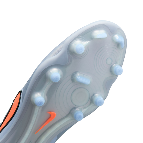 Close-up of the light grey soleplate of a soccer cleat, featuring light blue translucent studs and an orange Nike swoosh against a solid black background.
