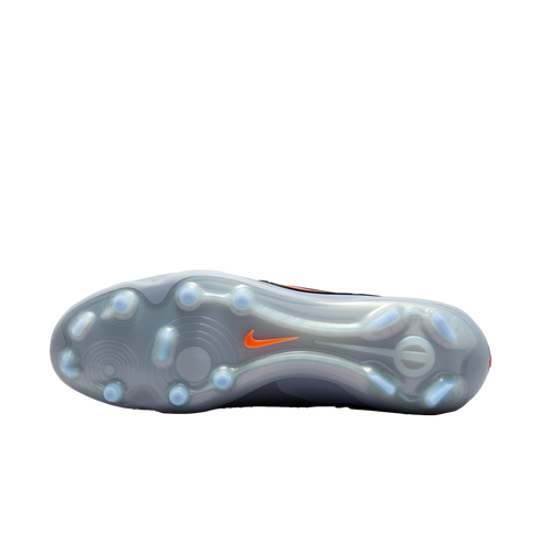 The translucent grey outsole of a Nike soccer cleat with a pattern of studs and an orange swoosh logo, shown against a solid black background.