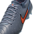 Close-up of a blue-grey Nike Tiempo soccer cleat with a vibrant orange swoosh and matching laces against a black background.