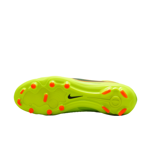 Underside of a lime green Nike soccer cleat with orange studs, set against a black background.