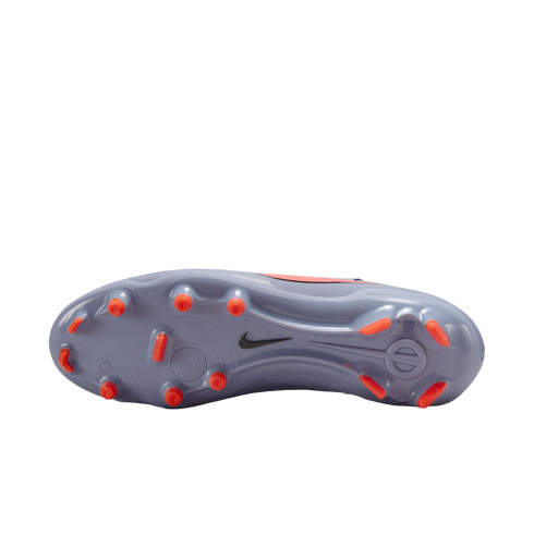 The lavender soleplate of a Nike soccer cleat featuring bright orange studs and a small black swoosh, isolated against a black background.