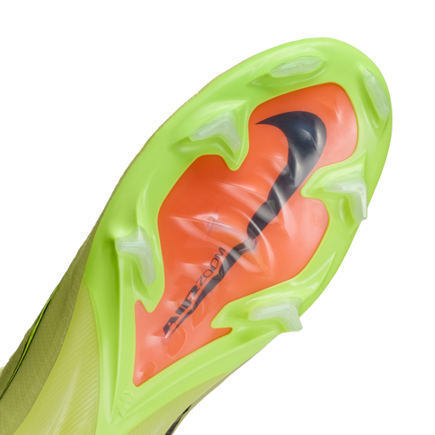 Underside of a lime green Nike soccer cleat with a bright orange 'Air Zoom' unit, black swoosh, and translucent studs.