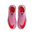 Top-down view of a pair of pink Nike Mercurial soccer cleats with bright orange swooshes on a black background.