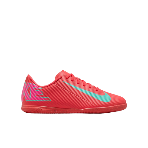 Side view of a bright pink Nike indoor soccer shoe with a teal swoosh and textured upper on a white background.