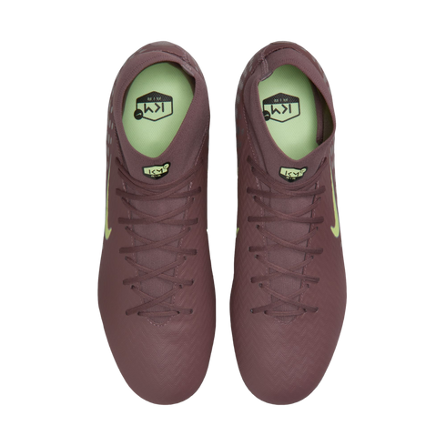 Top-down view of a pair of mauve Nike soccer cleats with neon green accents and "KM" branding on a black background.