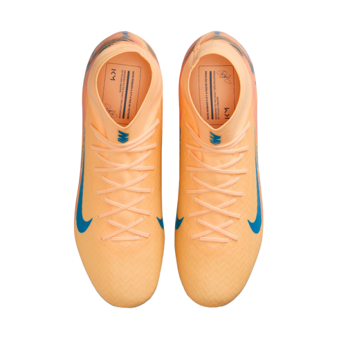 Top-down view of peach Nike Kylian Mbappé soccer cleats with blue accents on a black background.