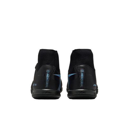 Rear view of black soccer shoes with light blue 'MERCURIAL' branding and high-top sock collars, set against a solid black background.