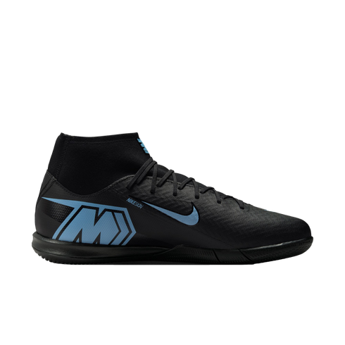 Profile of a black Nike Mercurial indoor soccer shoe with light blue accents, including a large "M" logo on the heel and a blue swoosh, set against a black background.