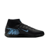 Profile of a black Nike Mercurial indoor soccer shoe with light blue accents, including a large "M" logo on the heel and a blue swoosh, set against a black background.