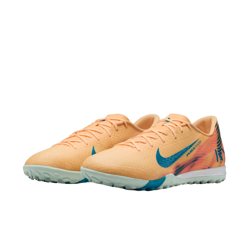 A pair of peach Nike Air Zoom Mercurial turf soccer shoes with teal swooshes and colorful heel graphics, isolated on a black background.