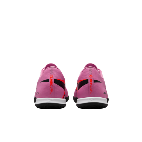 Rear view of two pink Nike Mercurial soccer shoes with red and black accents and white midsoles on a black background.