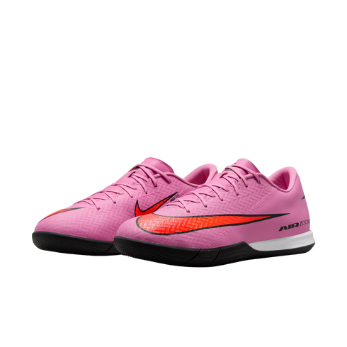 Pair of pink Nike Air Zoom indoor soccer cleats with a large orange swoosh on a solid black background.