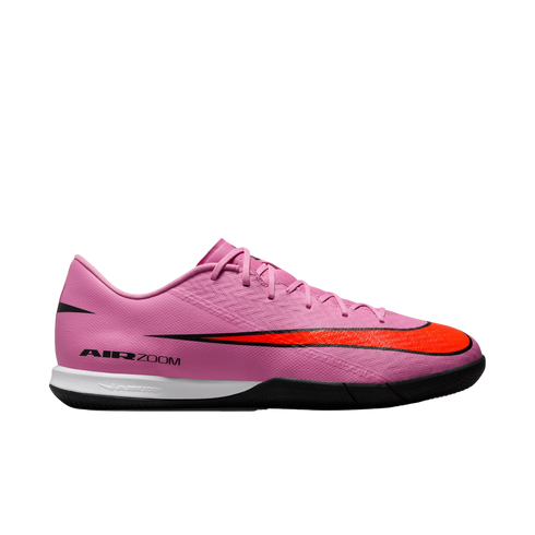 Profile view of a pink Nike soccer shoe with a large orange swoosh, black accents, white midsole, and black outsole.