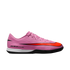 Profile view of a pink Nike soccer shoe with a large orange swoosh, black accents, white midsole, and black outsole.