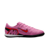 Profile view of a pink Nike indoor soccer shoe with red and black accents and a large "M" logo, isolated on a black background.