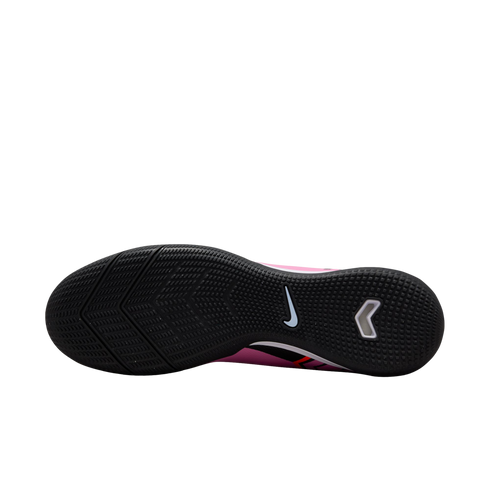Sole view of a pink Nike indoor soccer shoe with a textured black rubber outsole and a white swoosh logo.