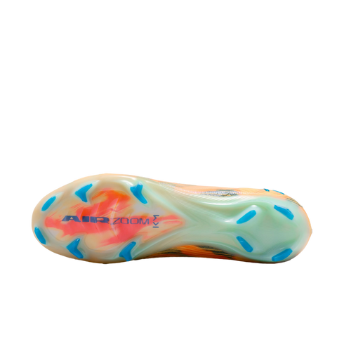Bottom of a Nike soccer cleat featuring a translucent soleplate with orange swirls, blue "AIR ZOOM" branding, and blue studs against a black background.