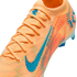 Close-up of an orange Nike soccer cleat with teal accents, featuring a textured knit upper, orange laces, and AIR ZOOM branding.