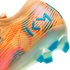 Close-up of an orange and pink soccer cleat featuring blue "KM" branding and blue studs on a translucent sole.
