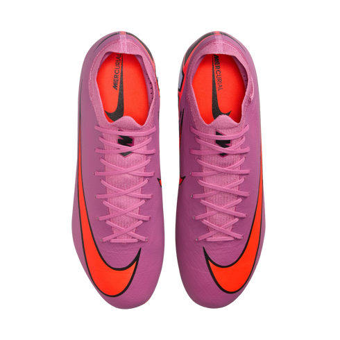 A top-down view of vibrant pink Nike Mercurial soccer cleats with large orange swoosh logos on the toes and bright orange interior lining, displayed against a black background.