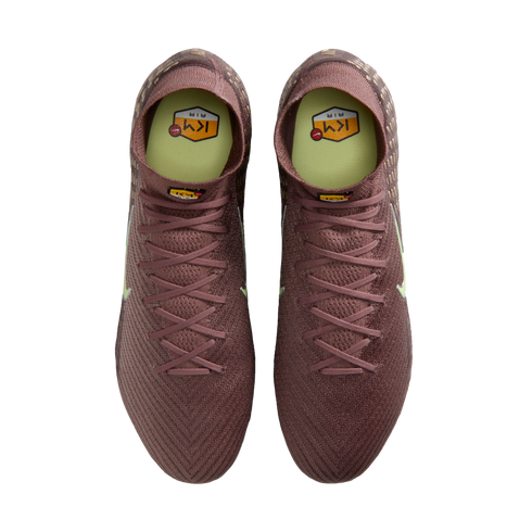 Top-down view of maroon Nike soccer cleats with neon yellow insoles and Kylian Mbappé "KM" branding, set against a solid black background.