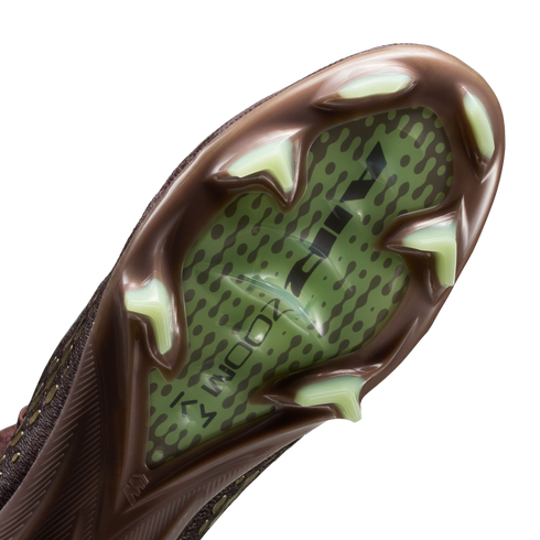 Close-up of a Nike soccer cleat's soleplate with a brown frame, light green triangular studs, and a translucent green center showing "AIR ZOOM" branding and a dotted pattern.