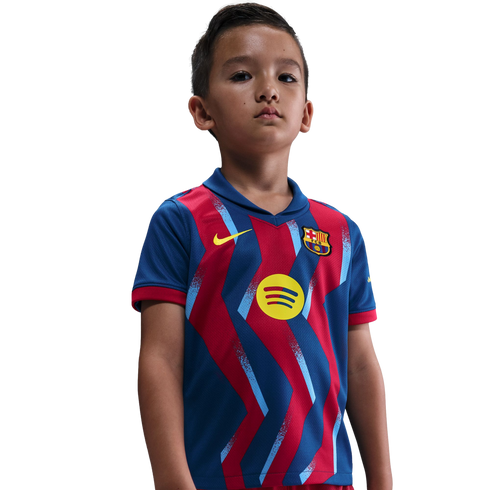 A young boy wearing a blue and red FC Barcelona soccer jersey with a yellow Spotify logo, standing against a black background.