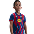 A young boy wearing a blue and red FC Barcelona soccer jersey with a yellow Spotify logo, standing against a black background.