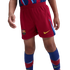 A person wearing red FC Barcelona football shorts with a yellow Nike swoosh and team crest, paired with blue and red patterned knee-high socks.