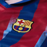 Close-up of an FC Barcelona soccer jersey featuring the embroidered club crest over red and blue vertical stripes.