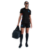 A woman standing in a black Nike England soccer kit and sunglasses, holding a black duffel bag.