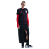 A woman in a striped black USA soccer jersey, red undershirt, long black skirt, and black sneakers, standing against a white background.