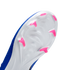Close-up of the white soleplate of a blue soccer cleat, featuring bright pink chevron-shaped studs against a black background.