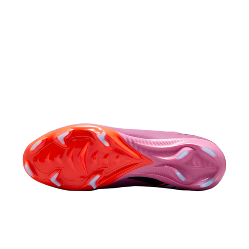 Bottom view of a Nike soccer cleat with an orange-to-pink gradient sole and white chevron-shaped studs, isolated against a black background.