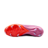 Bottom view of a Nike soccer cleat with an orange-to-pink gradient sole and white chevron-shaped studs, isolated against a black background.