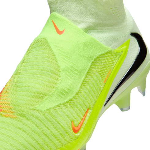 Close-up of a neon green laceless Nike soccer cleat with a textured knit upper and orange and black Nike swoosh logos.