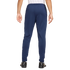 Rear view of a person wearing navy blue track pants and black soccer shoes against a plain white background.