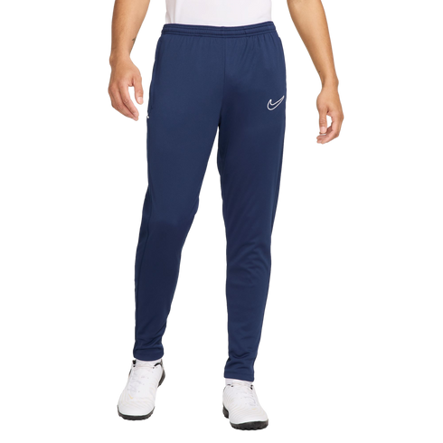 A person wearing navy blue Nike sweatpants with a white logo on the left leg and white athletic shoes.