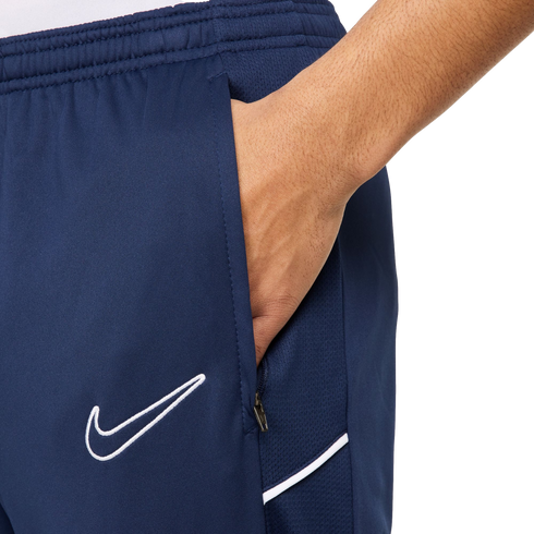 Close-up of a hand in the zippered pocket of navy blue Nike athletic shorts featuring a white swoosh logo.