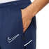 Close-up of a hand in the zippered pocket of navy blue Nike athletic shorts featuring a white swoosh logo.