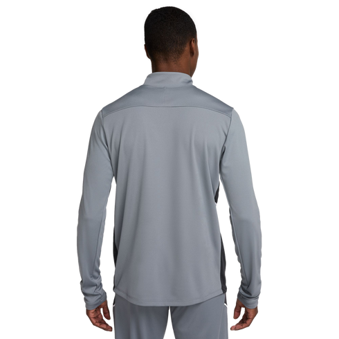 A man seen from behind wearing a grey athletic tracksuit set. The long-sleeved top features black side panels and a high collar.