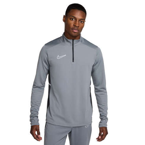 A man wearing a grey Nike half-zip long-sleeved athletic top and matching grey pants against a white background.
