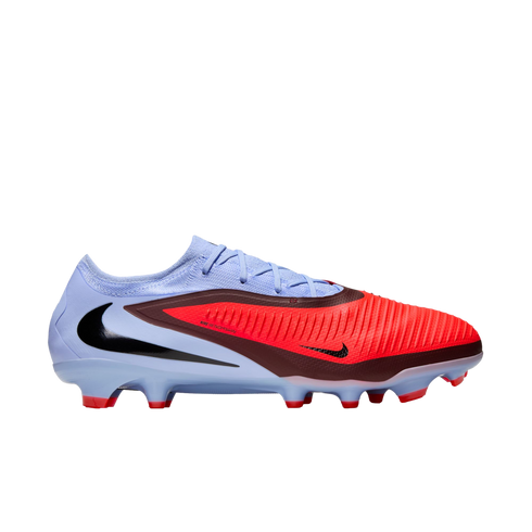 Profile view of a Nike soccer cleat with a light blue heel and a vibrant red, textured forefoot. Features a black swoosh and red studs against a black background.