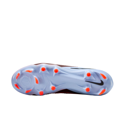 Underside view of a light blue Nike soccer cleat with bright orange studs and a black Nike swoosh, set against a black background.