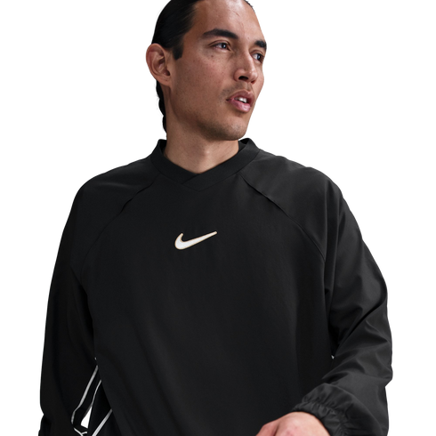 A man wearing a black long-sleeved Nike shirt with a white swoosh logo on the chest, looking to the side against a white background.