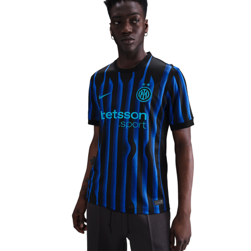 A man models the Inter Milan home jersey featuring black and blue wavy stripes, the Nike swoosh, club crest with two stars, and the Betsson Sport sponsor logo.