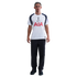 A man stands against a white background wearing a white and navy Tottenham Hotspur football shirt, black trousers, and black trainers.