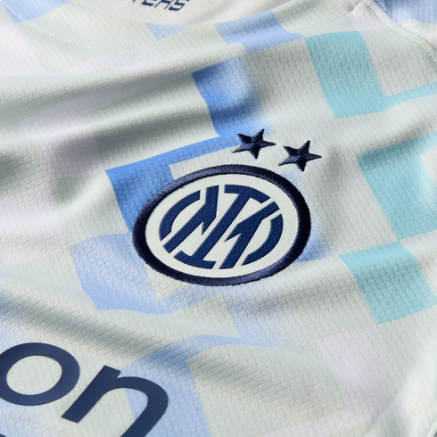 Close-up of an Inter Milan soccer jersey with a light blue and white checkered pattern and the team crest with two stars above it.